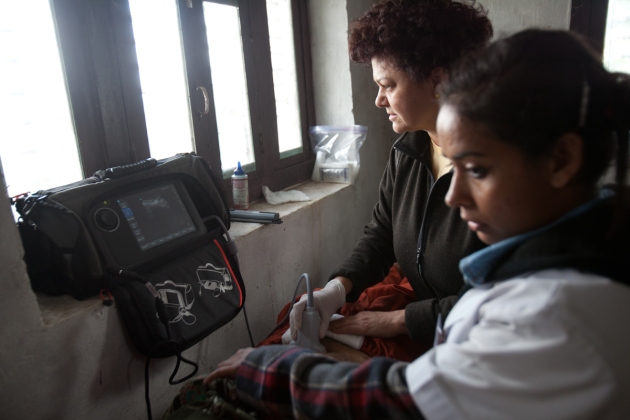 A Nepali woman receives an ultrasound while a Nepali nurse learns to operate the machine.